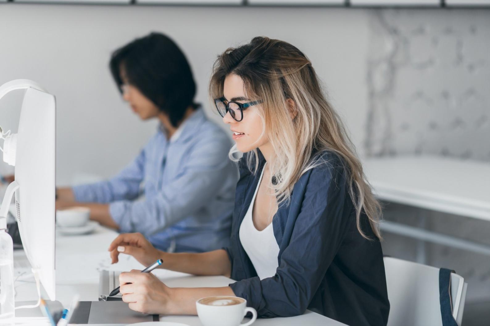 Student working on website design layout with multiple screens showing responsive design variations